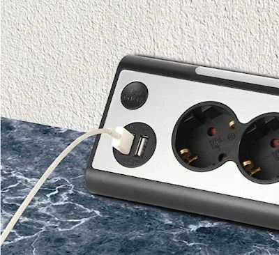 Regleta de enchufes instalada sobre la encimera de una cocina para conectar pequeños electrodomésticos