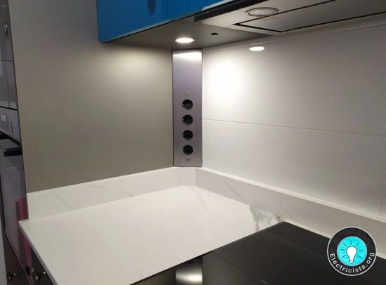 Regleta de enchufes esquinera instalada en una cocina real bajo los muebles altos